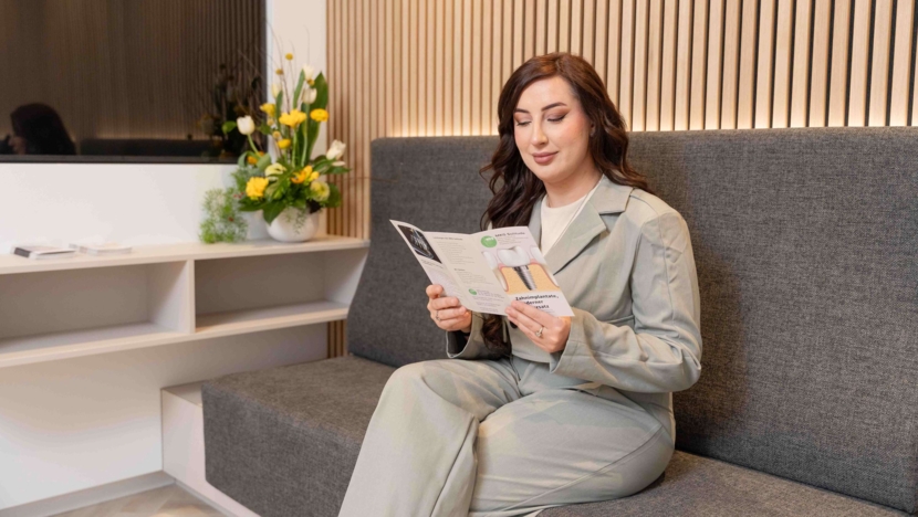 Patientin sitzt im modernen Wartezimmer und liest eine Broschüre