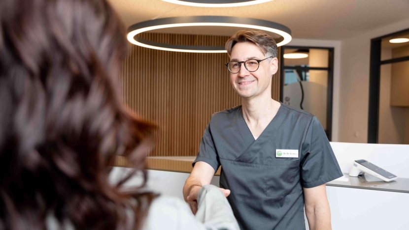 Dr. Dr. Santo begrüßt eine Kooperationspartnerin in der Praxis